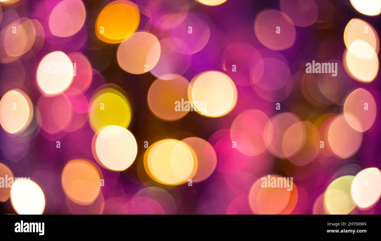 Yellow and purple glitter and abstract festive elegant background with blurred bokeh lights. Defocused holiday lighting. Stock Photo