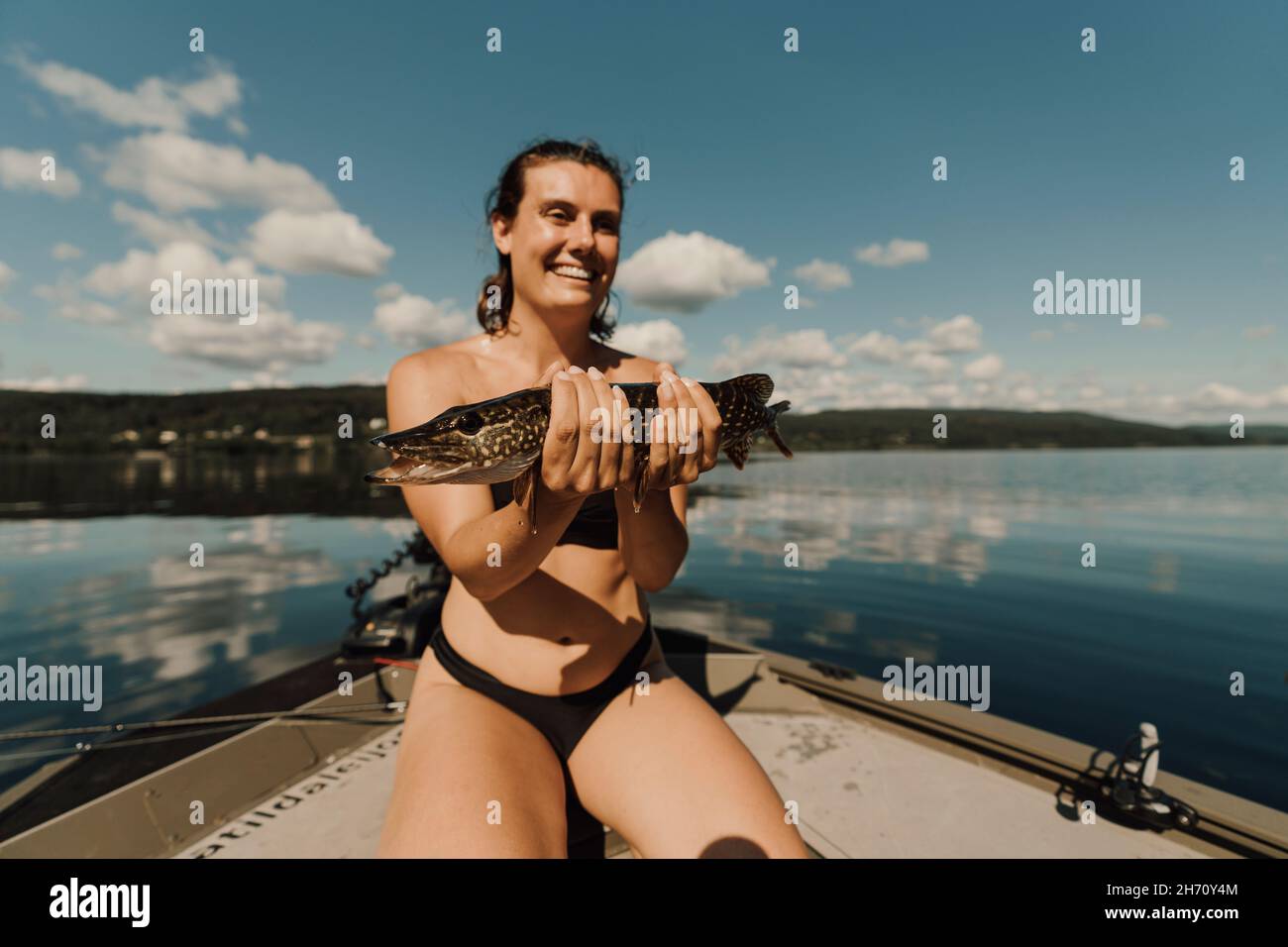 Smiling woman on boat holding fish Stock Photo