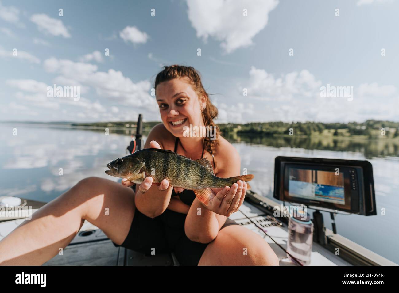 Smiling woman on boat holding fish Stock Photo