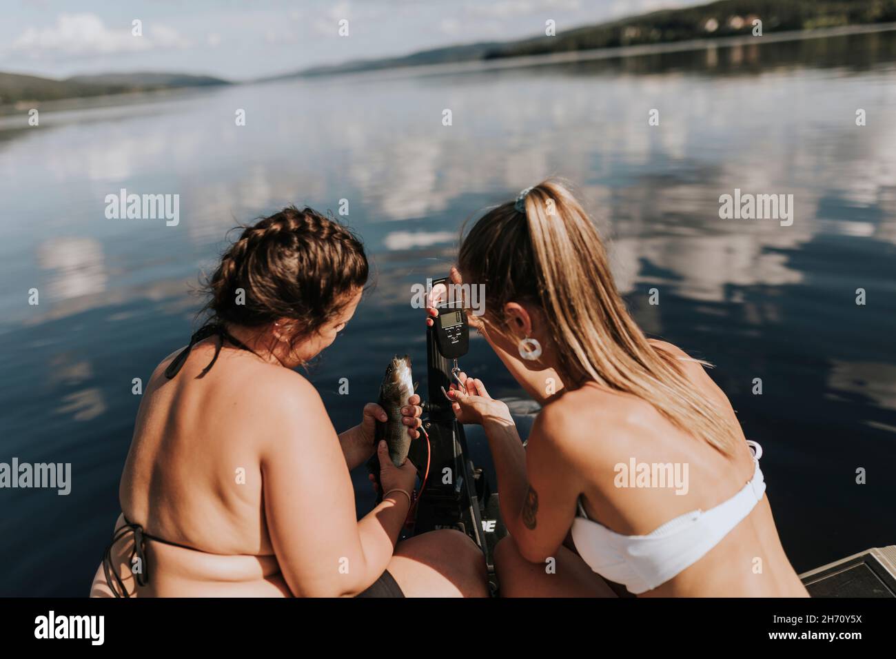 Women on boat taking photo of fish Stock Photo