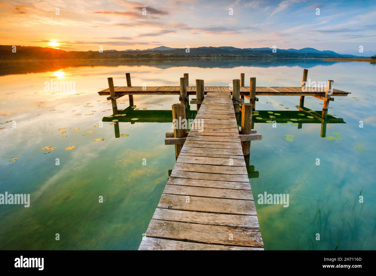 Wooden jetty on the lake Pfaeffikersee at sunrise. Pfaeffikon, Canton of Zurich, Switzerland Stock Photo