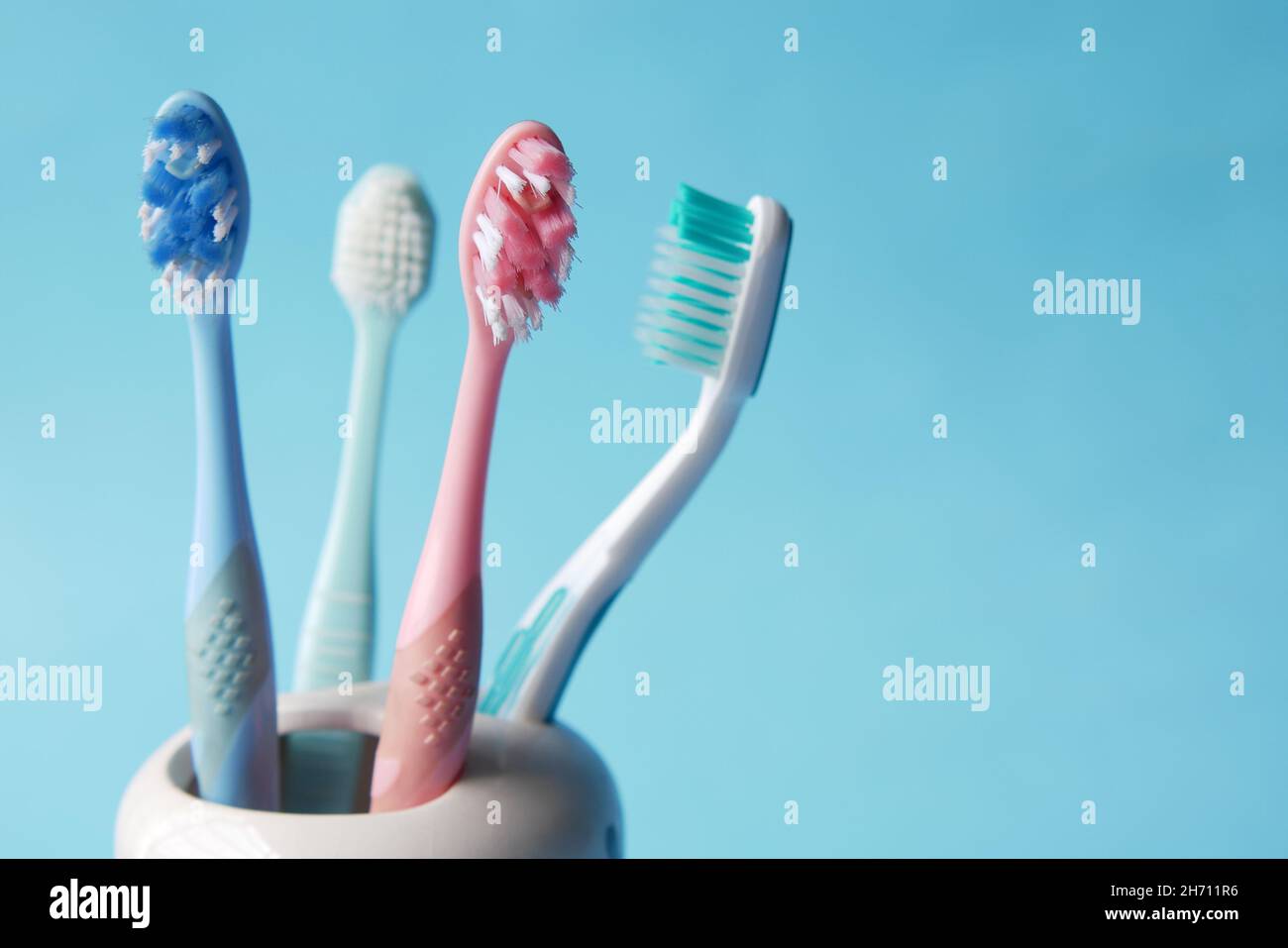colorful toothbrushes in white mug against a wall Stock Photo - Alamy