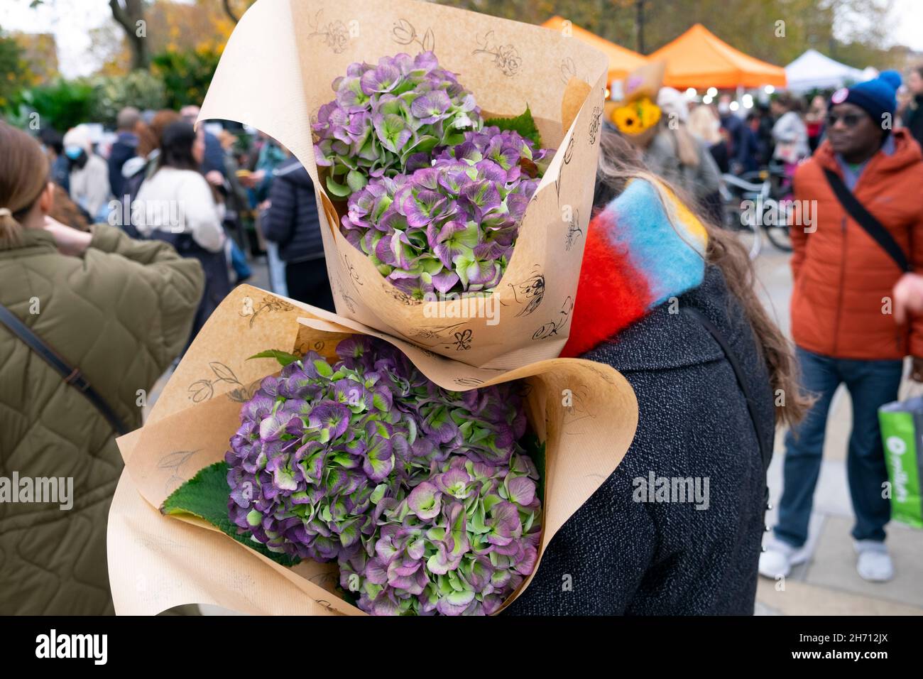 Columbia Road Flower Market people buying plants flowers in the street at market stalls on Sunday in November 2021 East London UK KATHY DEWITT Stock Photo
