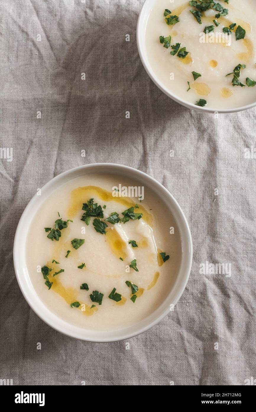 Two bowls of creamy celeriac soup topped with a drizzle of olive oil and chopped parsley. Stock Photo