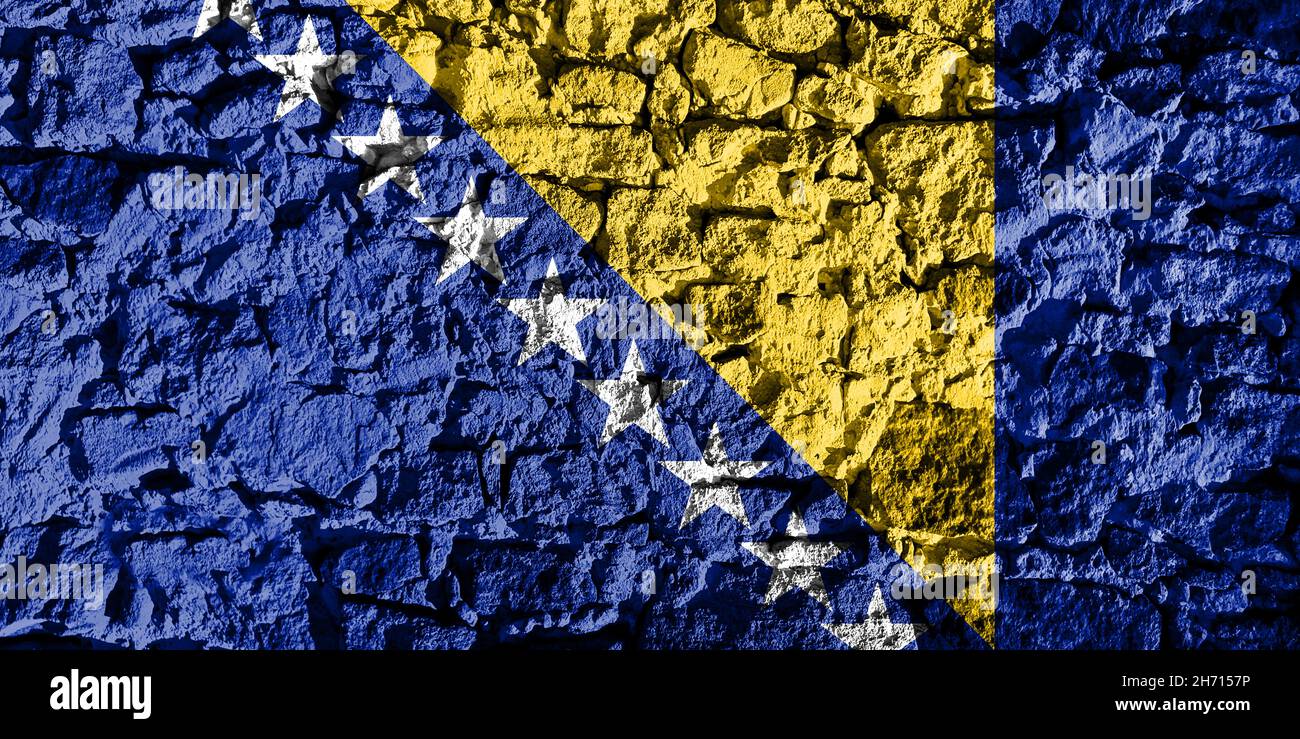 Bosnia and Herzegovina flag depicted on a stone wall. The texture of the stone blends perfectly with the colors of the banner Stock Photo