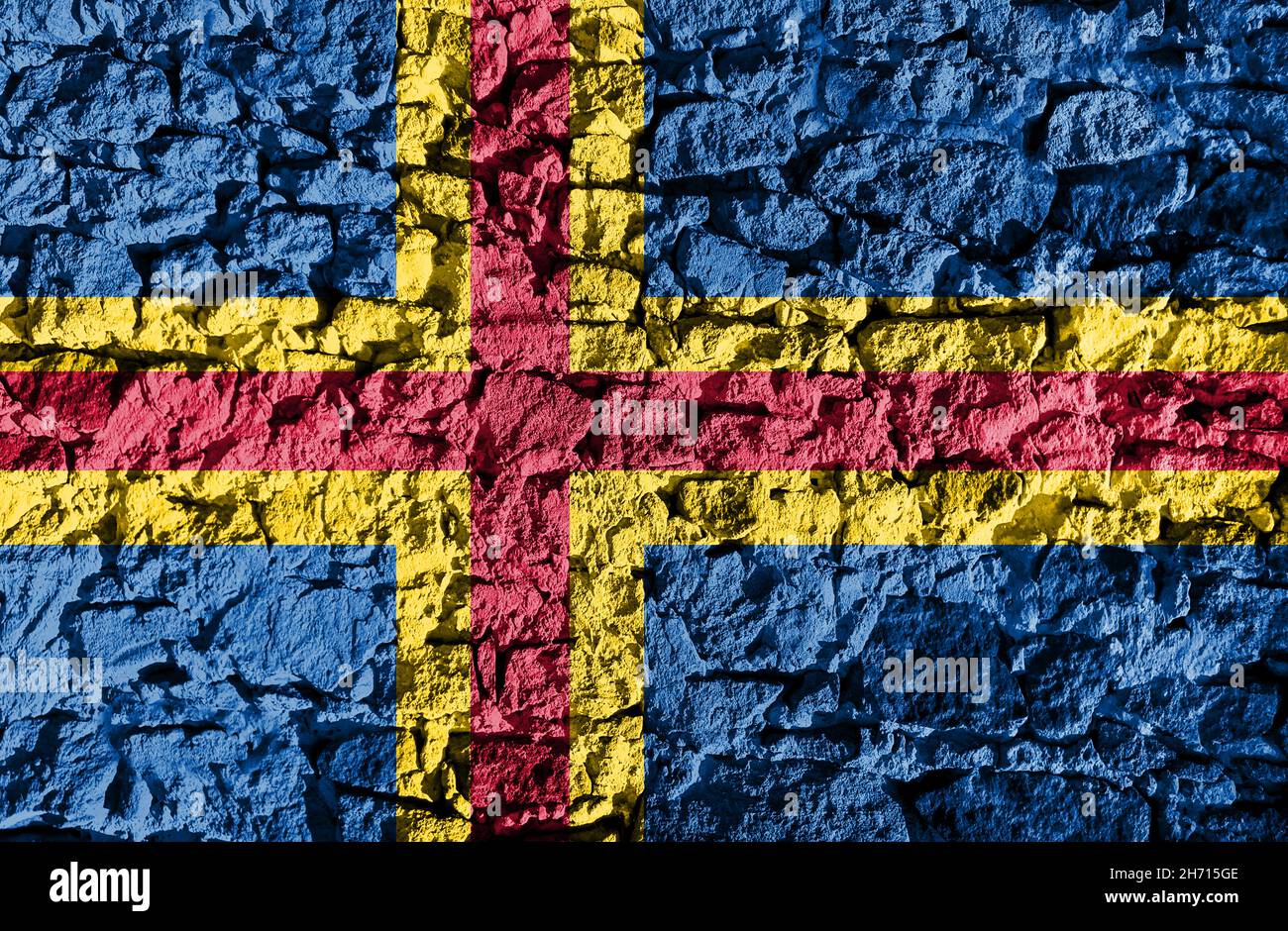 Aland Islands flag depicted on a stone wall. The texture of the stone blends perfectly with the colors of the banner Stock Photo