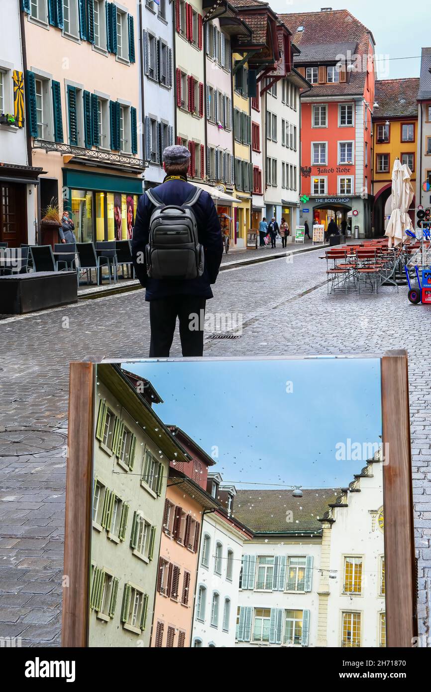 Aarau, Switzerland - November 3, 2021: A man visits the old town of Aarau, the capital of the northern Swiss canton of Aargau. A street mirror reflect Stock Photo