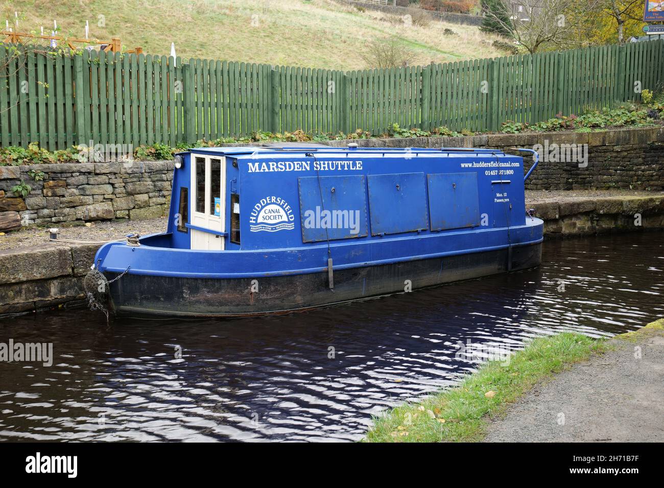 Marsden Shuttle small blue canal barge moored green wooden fence in the background Stock Photo