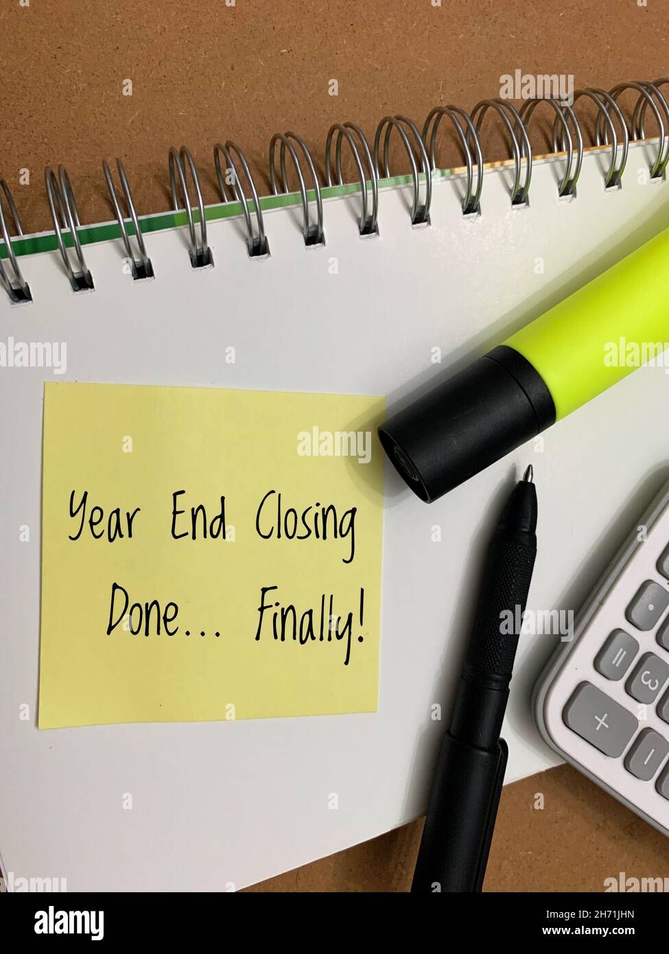 Completed year end closing text on sticky pad with calculator, highlighter and pen background Stock Photo