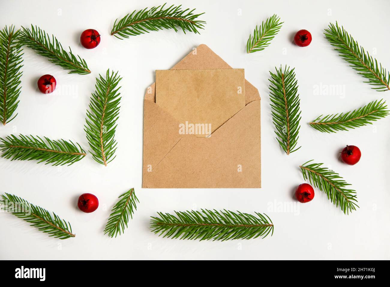 Closeup eco beige craft envelope, letter to Santa. Frame of fir branch or spruce branch and red berries isolated on white background. Fir tree Stock Photo
