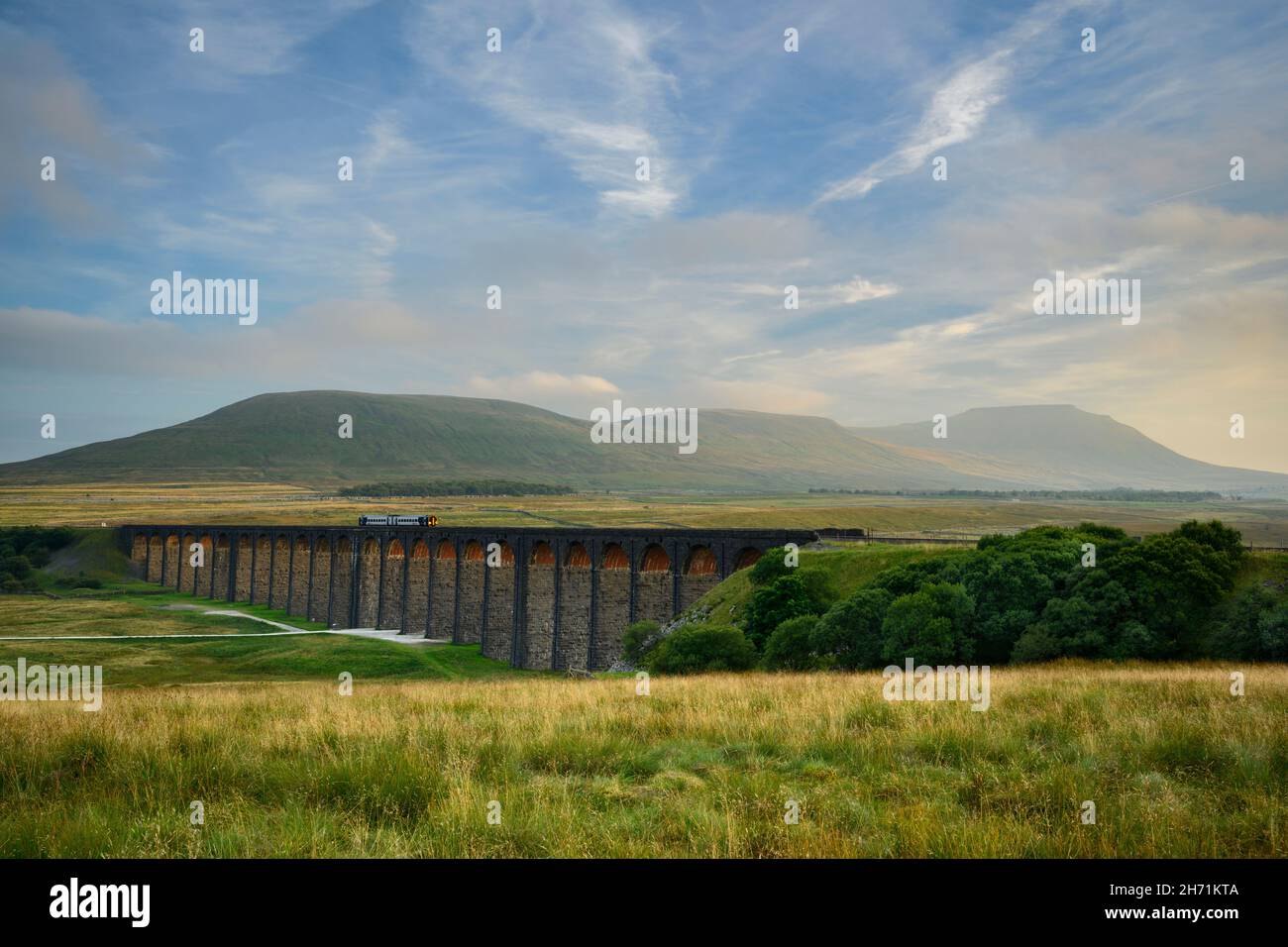 Scenic countryside valley (locomotive on landmark Ribblehead Viaduct, sunlight on arches, high hills & mountain) - North Yorkshire Dales, England UK. Stock Photo