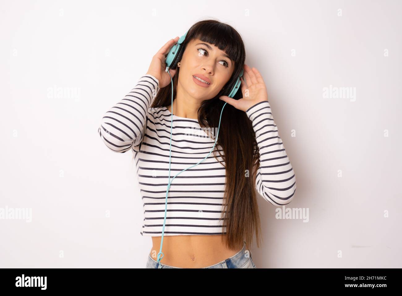 Beautiful young woman with long hair wearing headphones listening music ...