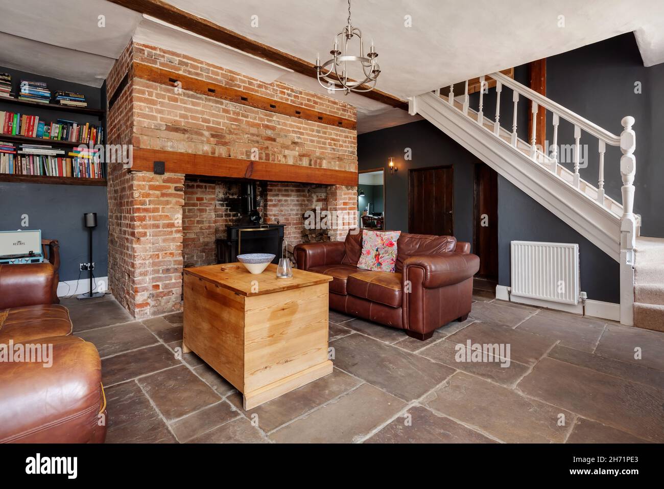 Ashdon, England  - July 25 2019: traditional farmhouse living room inside British home with large exposed brick inglenook fireplace and stone floor Stock Photo