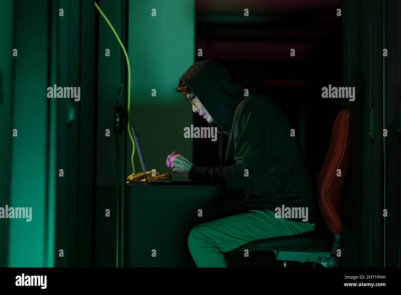 Asian male hacker using a laptop in computer server room Stock Photo