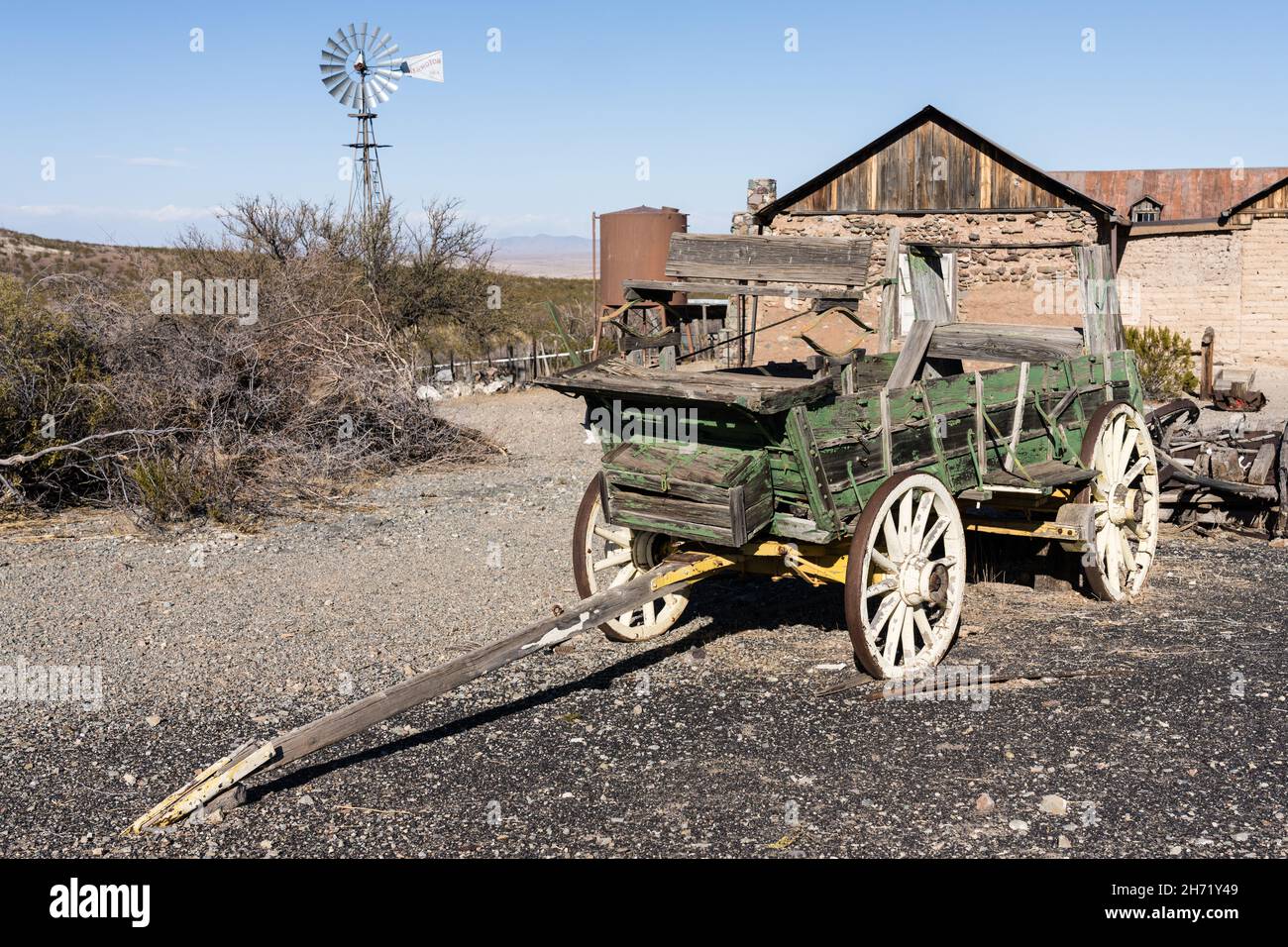 An old broken down ranch chuck wagon with a windbill behind in the