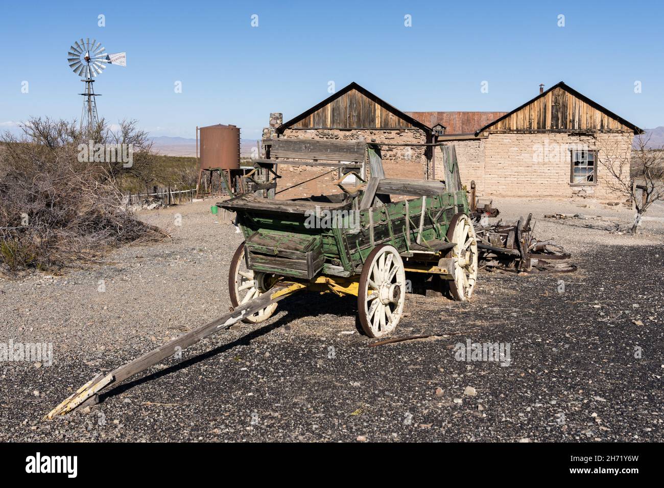 An old broken down ranch chuck wagon with a windbill behind in the