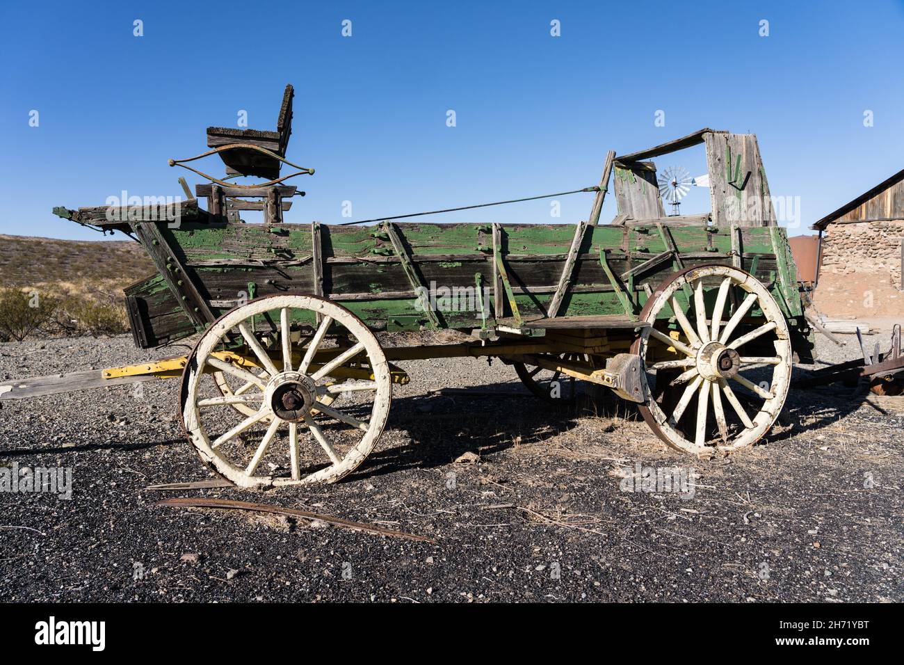 An old broken down ranch chuck wagon with a windbill behind in the