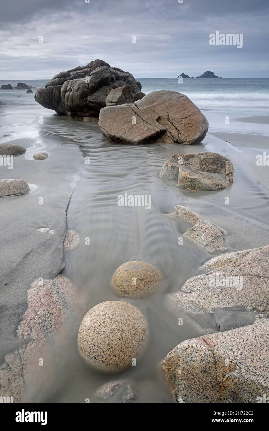View of Porth Nanven beach showing the granite boulders with the Brisons in the background Cornwall Stock Photo