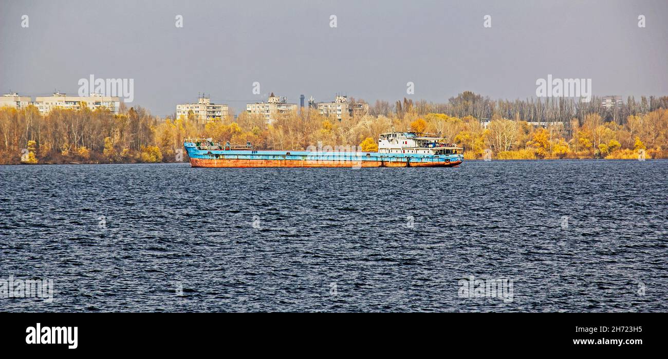 An articulated tug and bulk barge transport sand and construction materials along the river. A large barge sails along the wide Dnieper River. Transpo Stock Photo