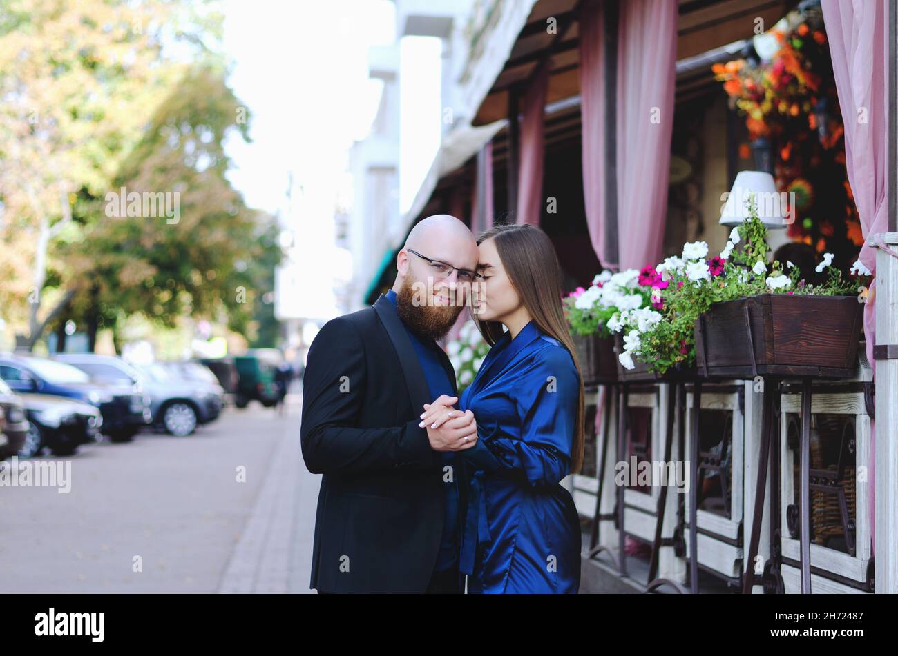 Happy family, couple drinking coffee in city. Urban love story of a stylish young business man in a blue suit with a red beard. And attractive woman Stock Photo