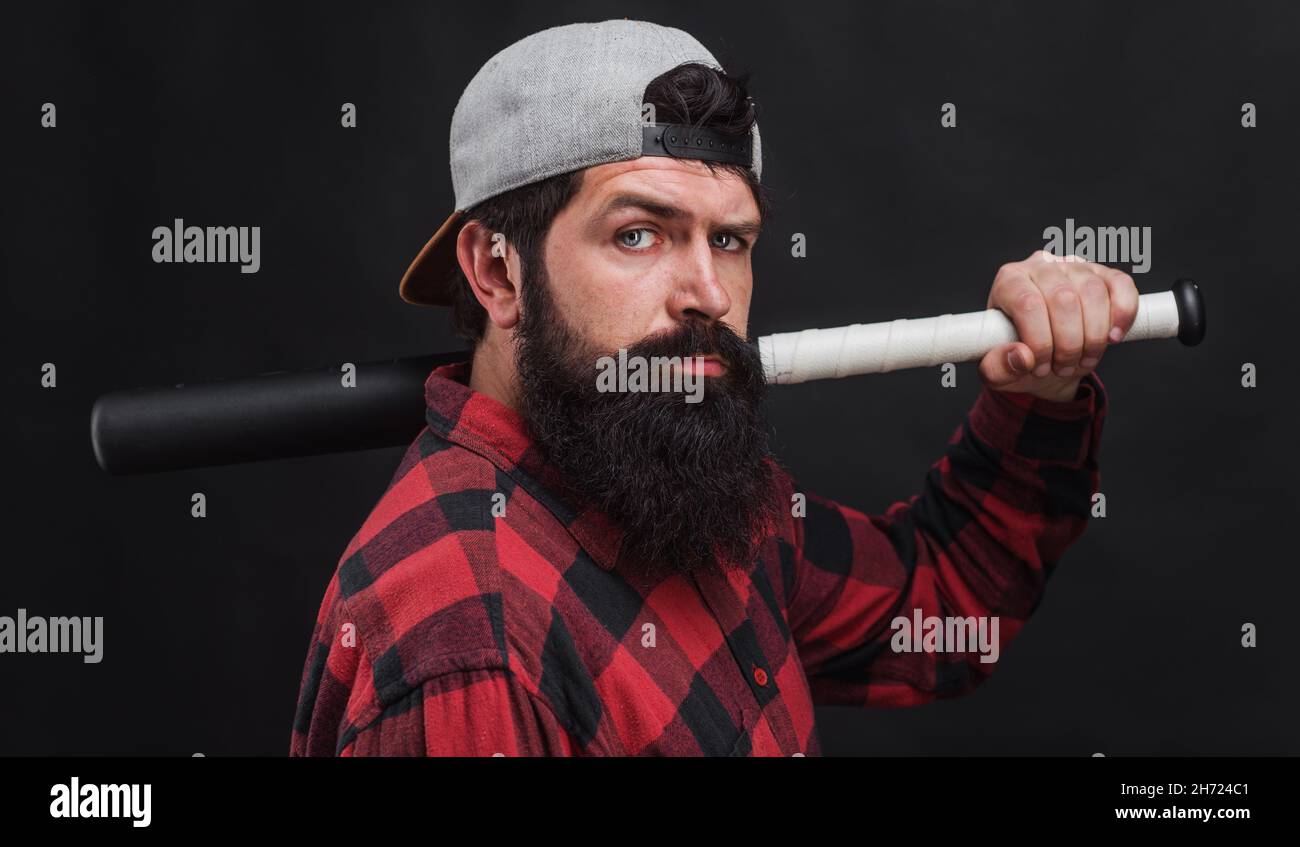 Bearded man with baseball bat. Sports equipment. Baseball player in cap and checkered shirt. Sports and baseball training concept. Stock Photo