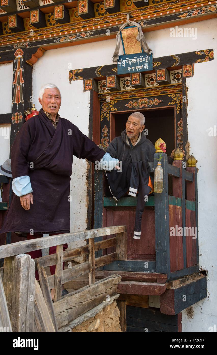 Two elderly Bhutanese men in the doorway of a farmhouse by the Tamchhog Lhakhang Temple near Paro, Bhutan. Stock Photo
