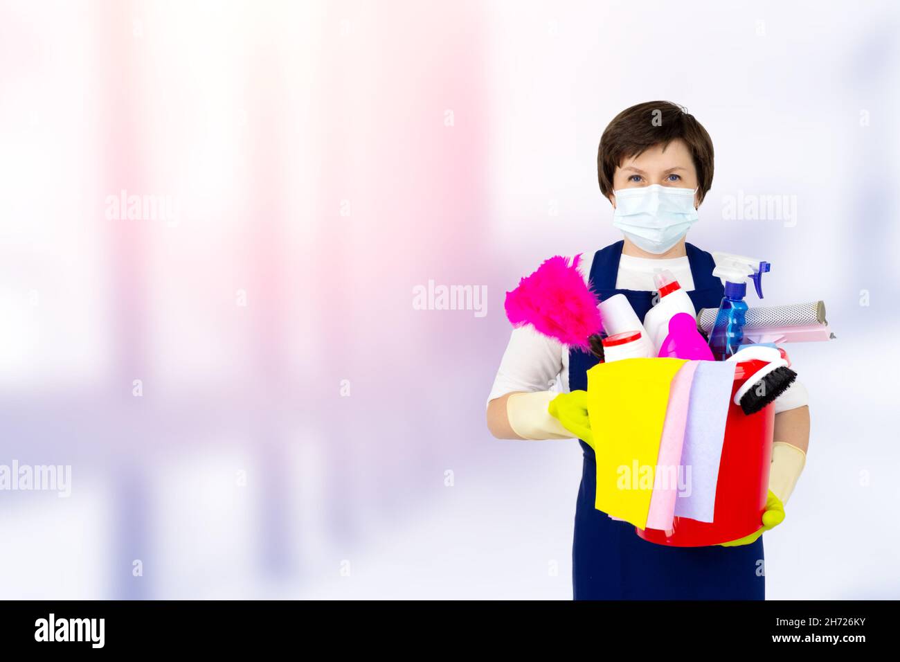 Cleaning lady in uniform and yellow rubber gloves holding a bucket of ...