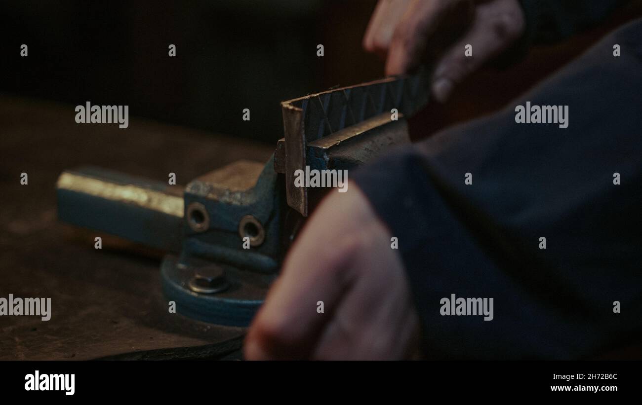Closeup at part of a rustic old metal grip clamp, young blacksmith clamps the metal or iron