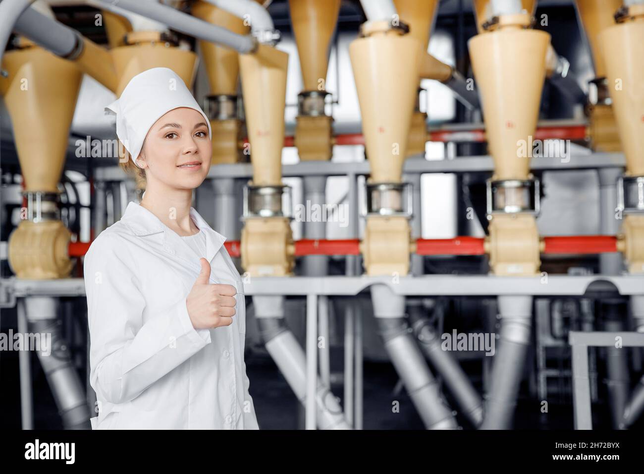 Modern electrical mill machinery for production of wheat flour. Woman operator on background