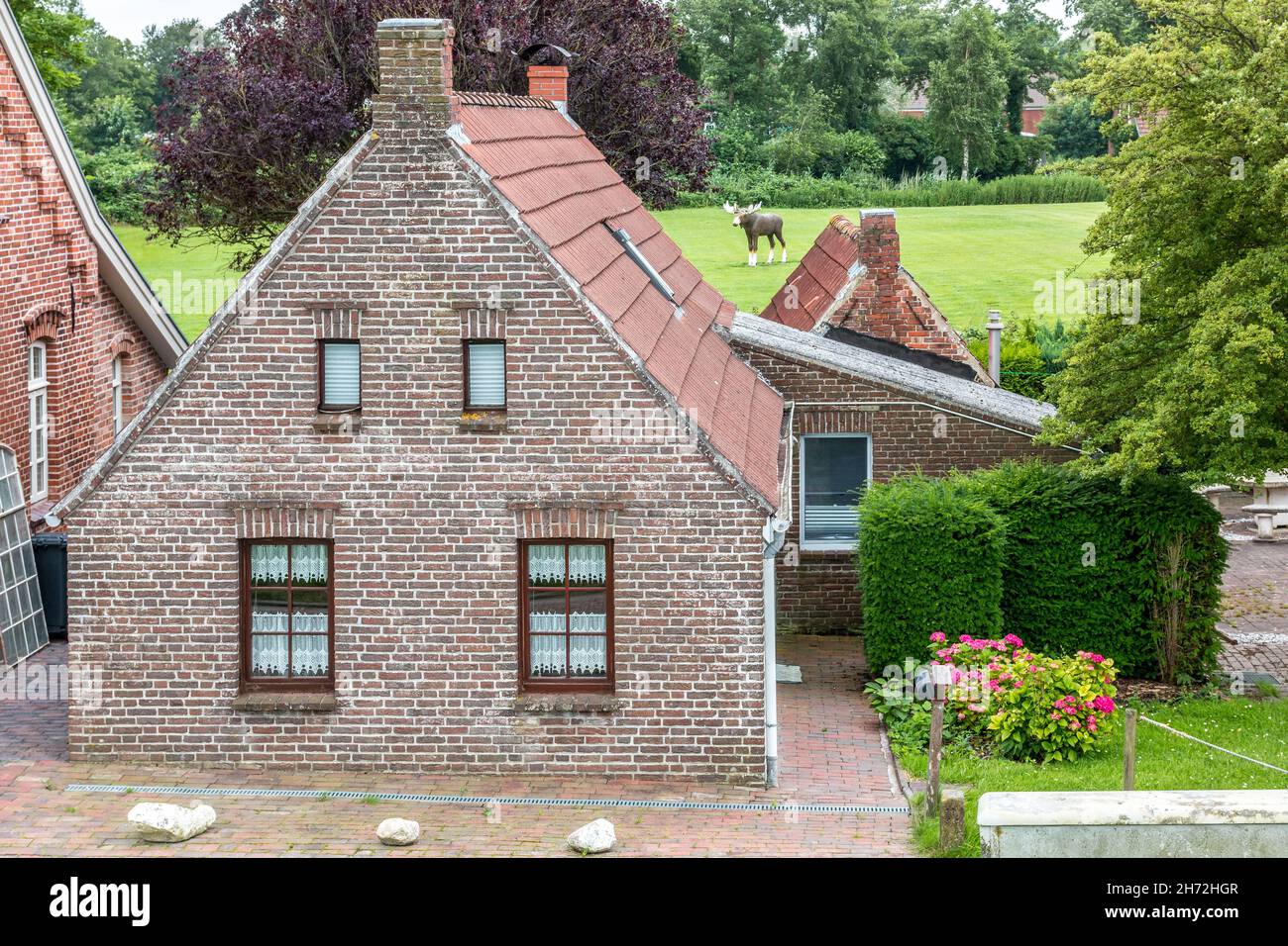 House made of red clincker bricks surrounded by green trees Stock Photo