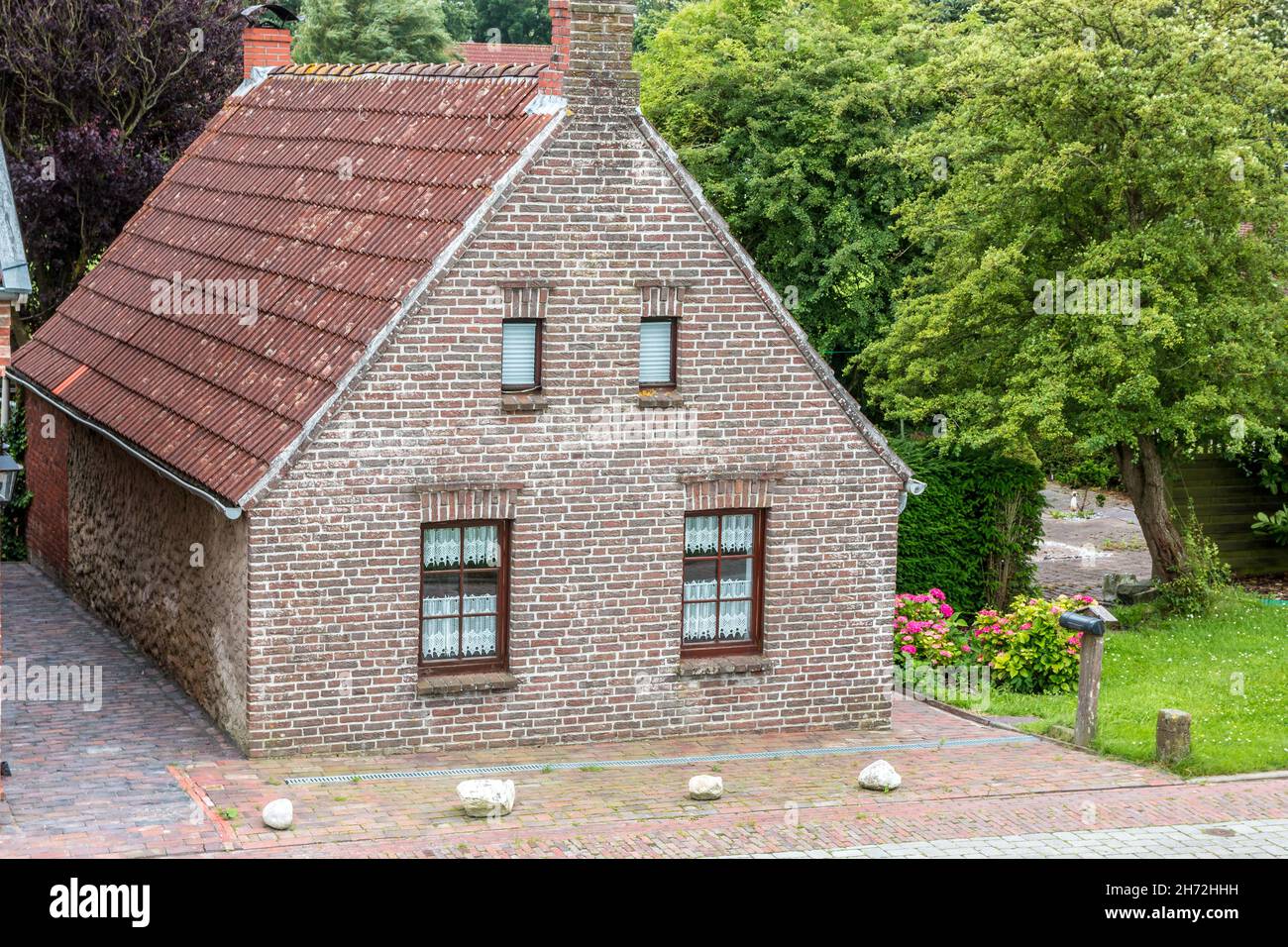 House made of red clincker bricks surrounded by green trees Stock Photo