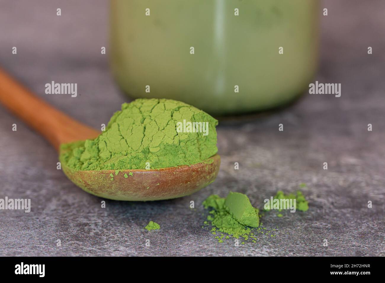 A close up of a scoop of matcha green tea powder with a matcha latte