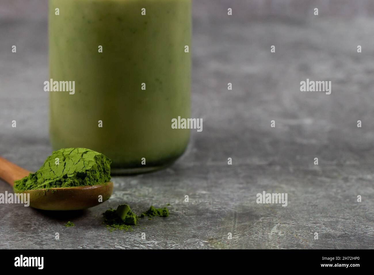 A close up of a scoop of matcha green tea powder with a matcha latte