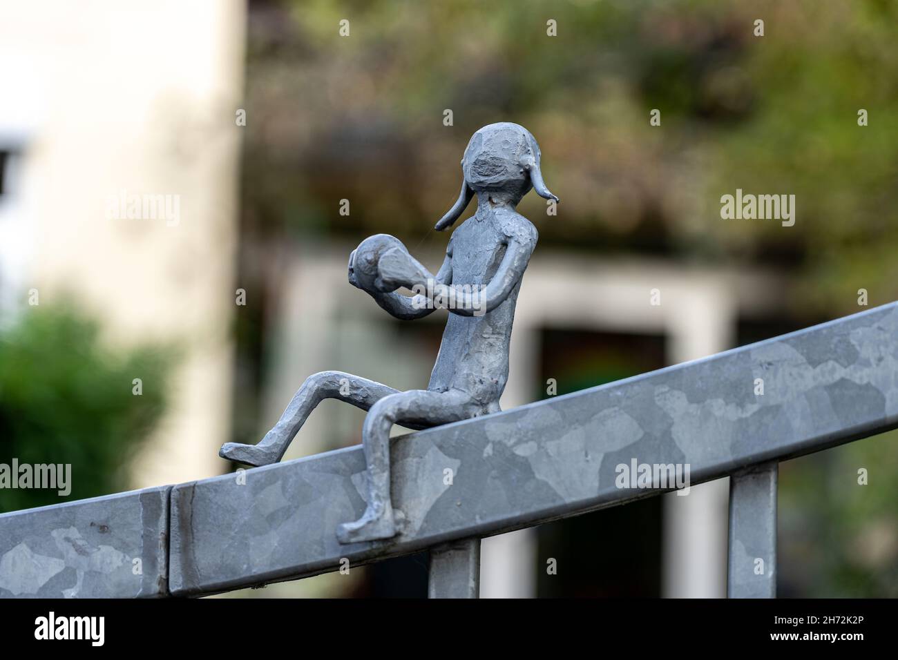 Little figures made of steel on a metal fence in shape of playing kids Stock Photo