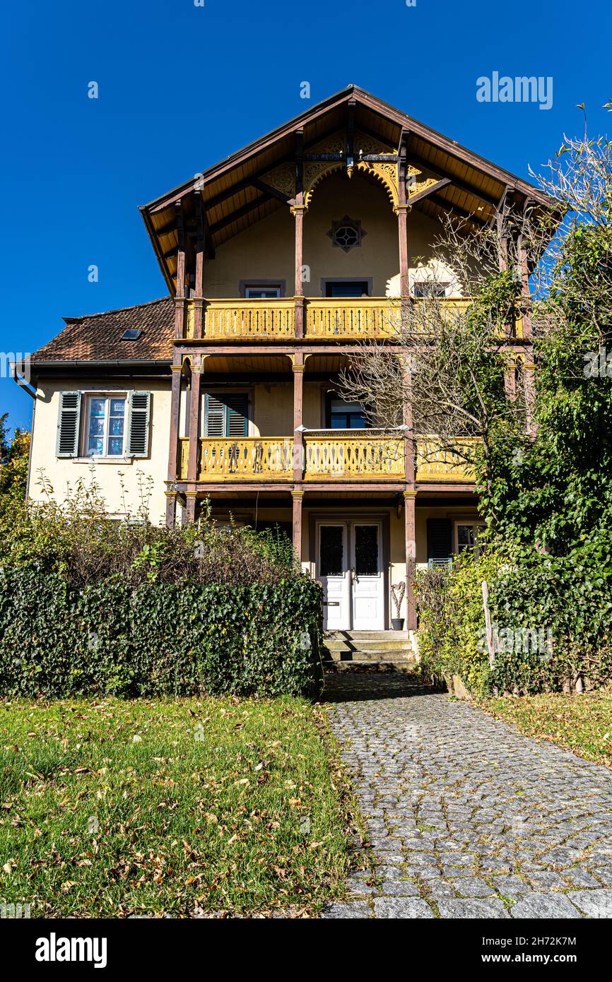 Wooden cottage with yellow balconies and green garden Stock Photo