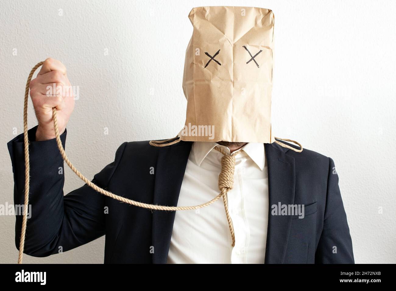 business man or broker in dark suit, with paper bag on it's head, wearing a rope as a tie. Stock Photo