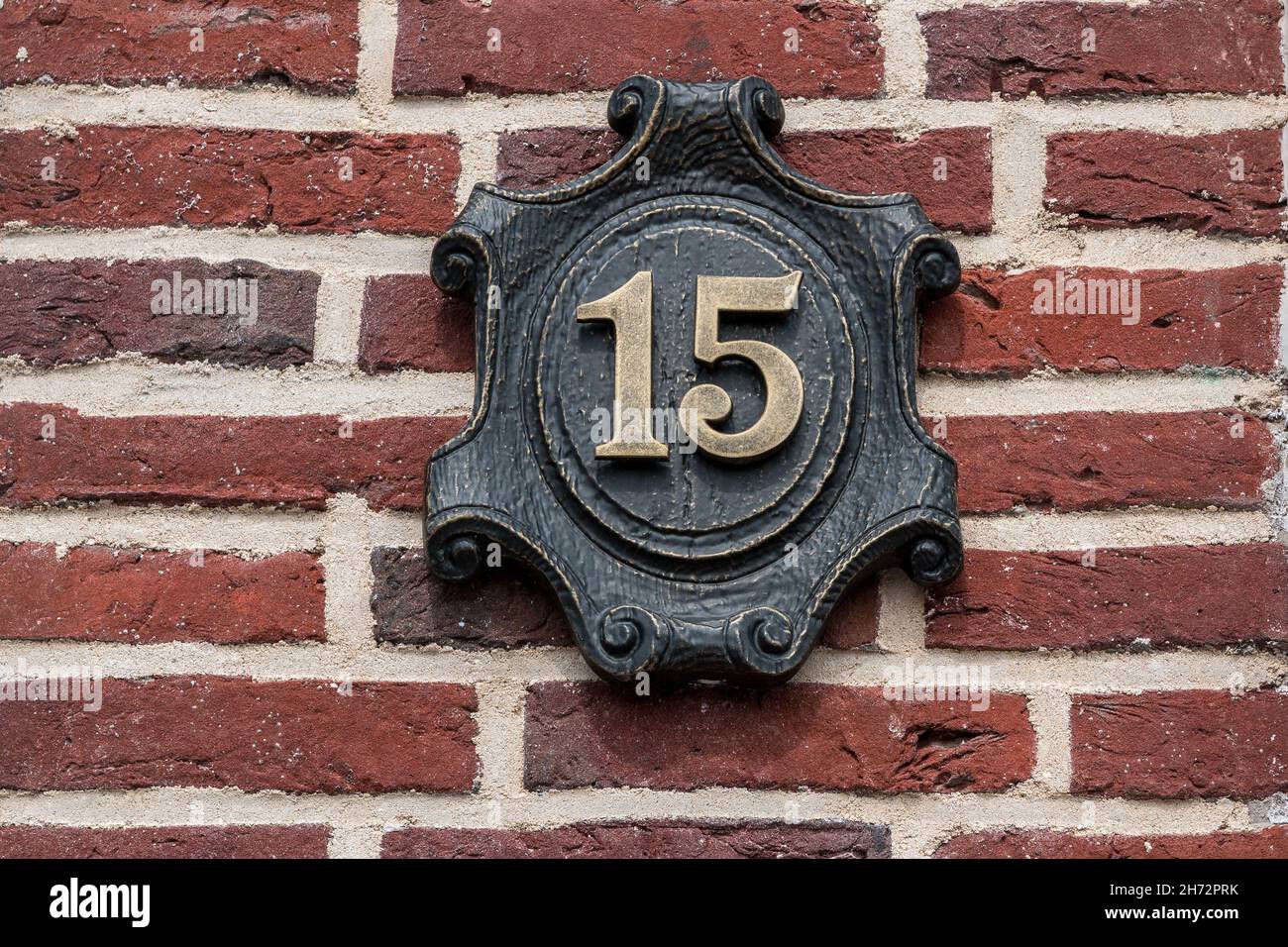 House number made of metal on a brick wall Stock Photo