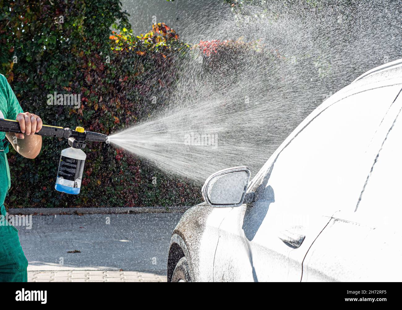 Man washing her car in car wash .A man washes a car in a manual car
