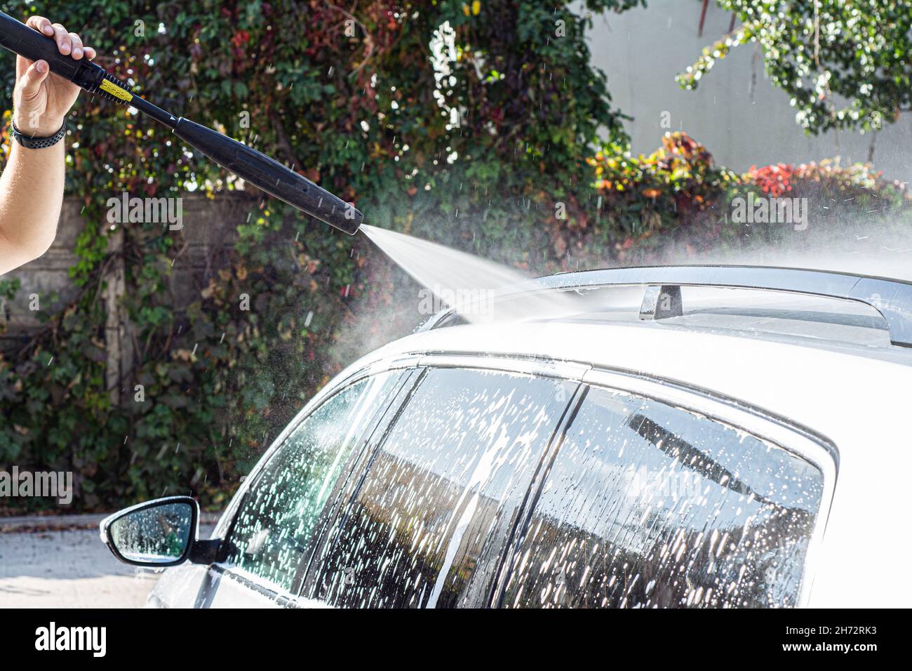 Man washing her car in car wash .A man washes a car in a manual car