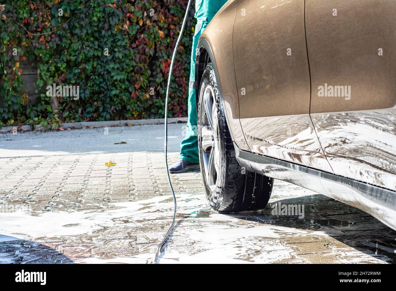 Man washing her car in car wash .A man washes a car in a manual car