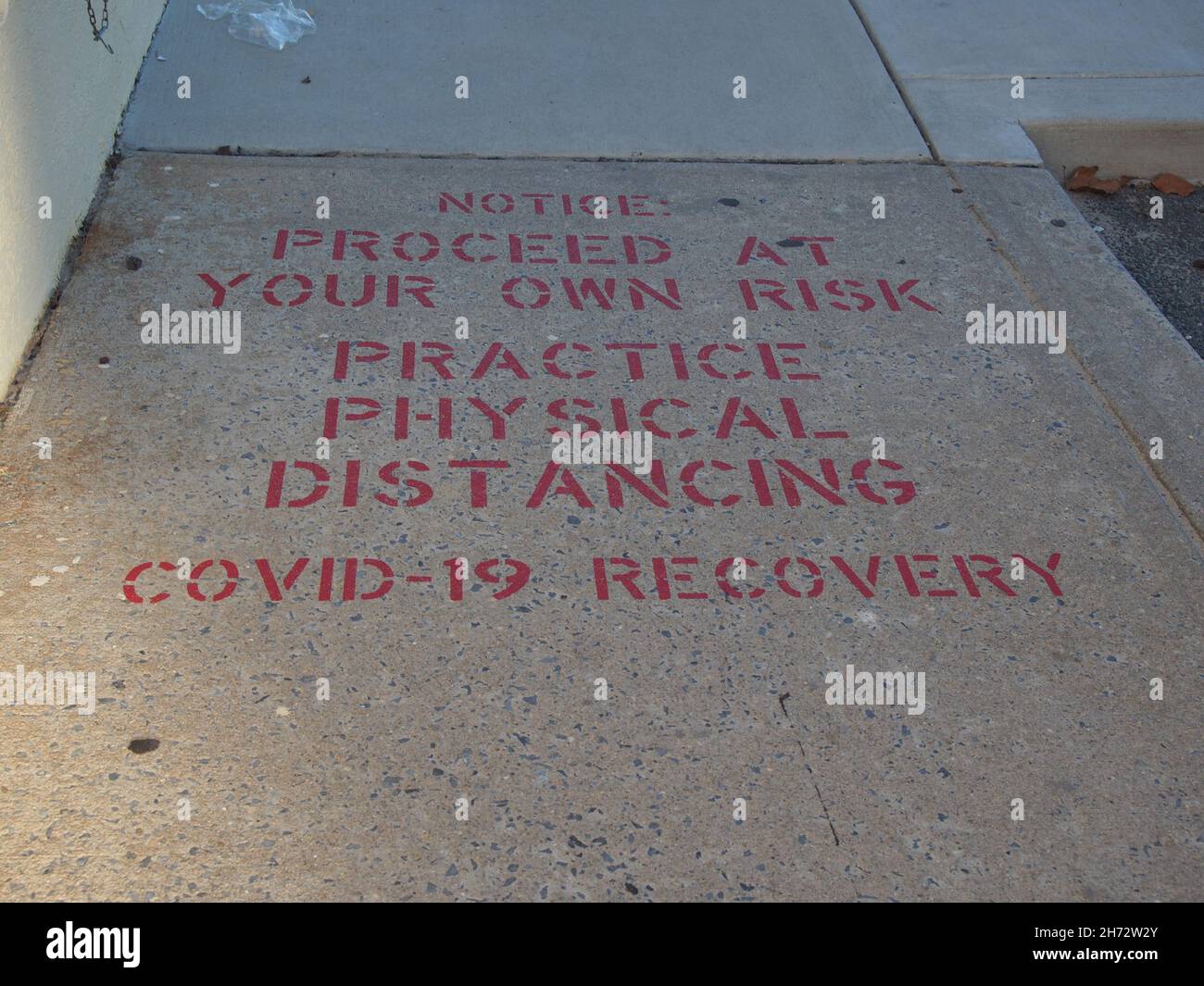 Practice physical distancing message stenciled on a sidewalk near the boardwalk at Ocean City, Maryland, USA, 2021, © Katharine Andriotis Stock Photo