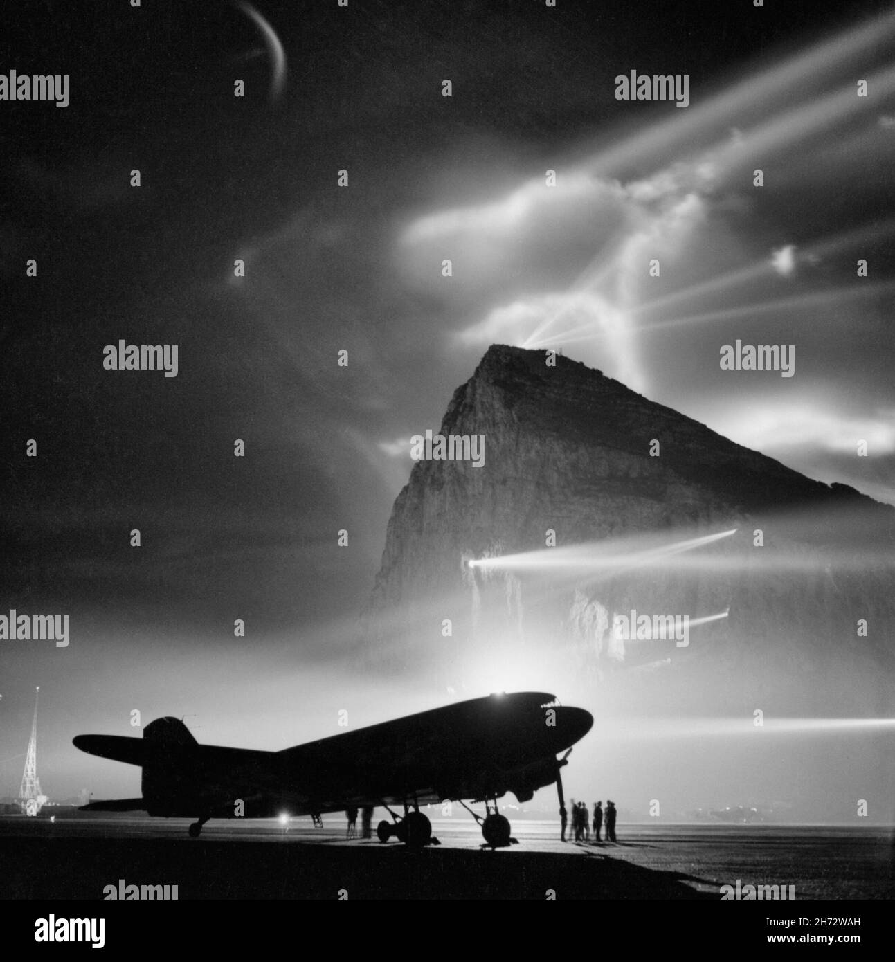 A Douglas Dakota of BOAC, silhouetted by night at Gibraltar by the batteries of searchlights on the Rock, as it is prepared for a flight to the United Kingdom between 1940 and 1945 Stock Photo