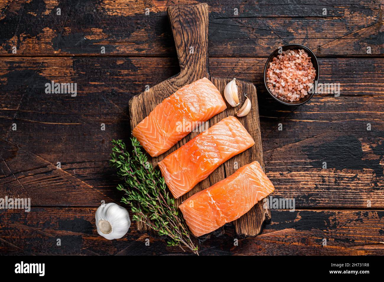 Fresh Raw salmon fish fillet steaks on wooden board with thyme. Dark ...