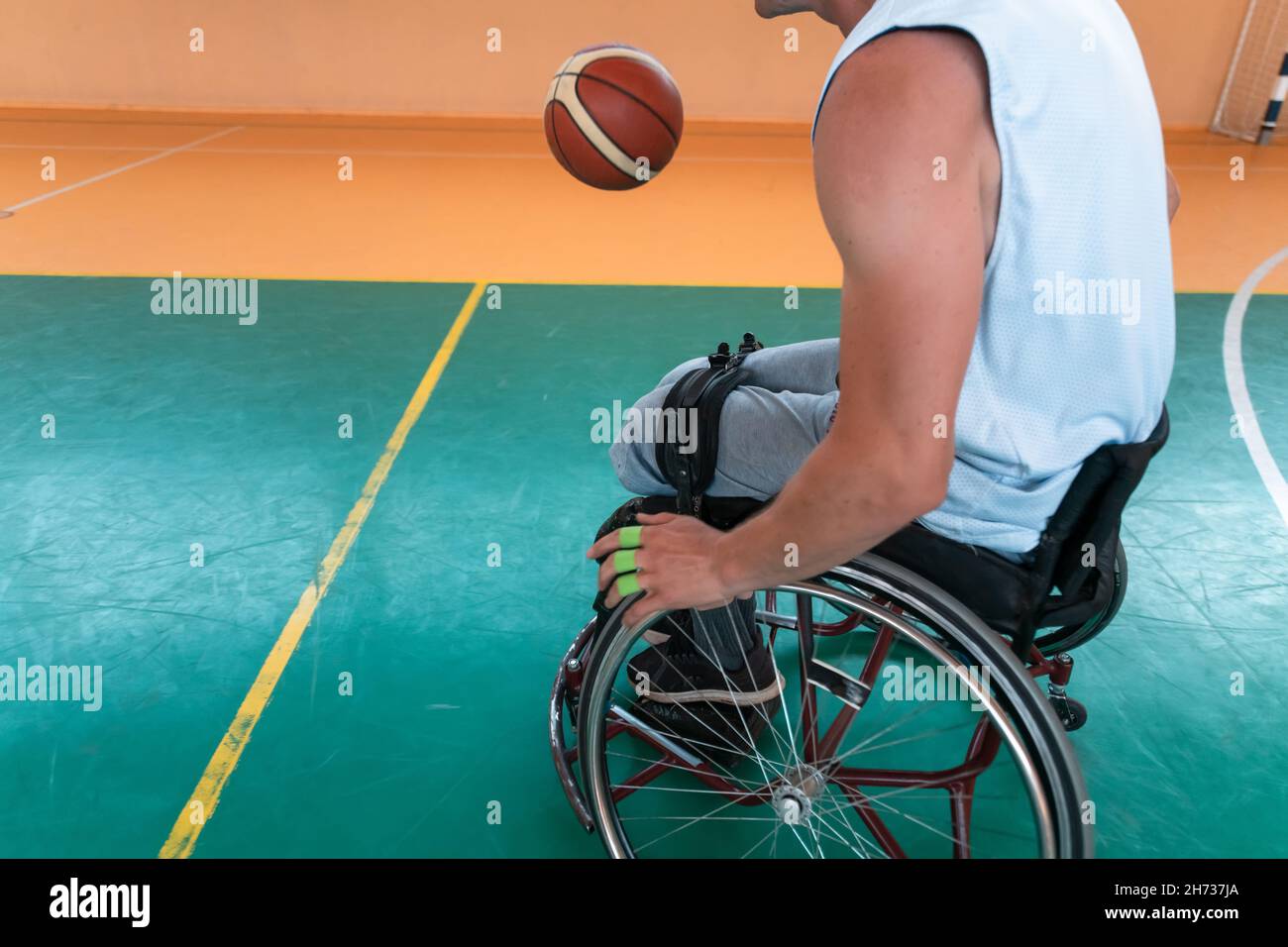 Disabled War veterans mixed race and age basketball teams in wheelchairs playing a training match in a sports gym hall. Handicapped people Stock Photo