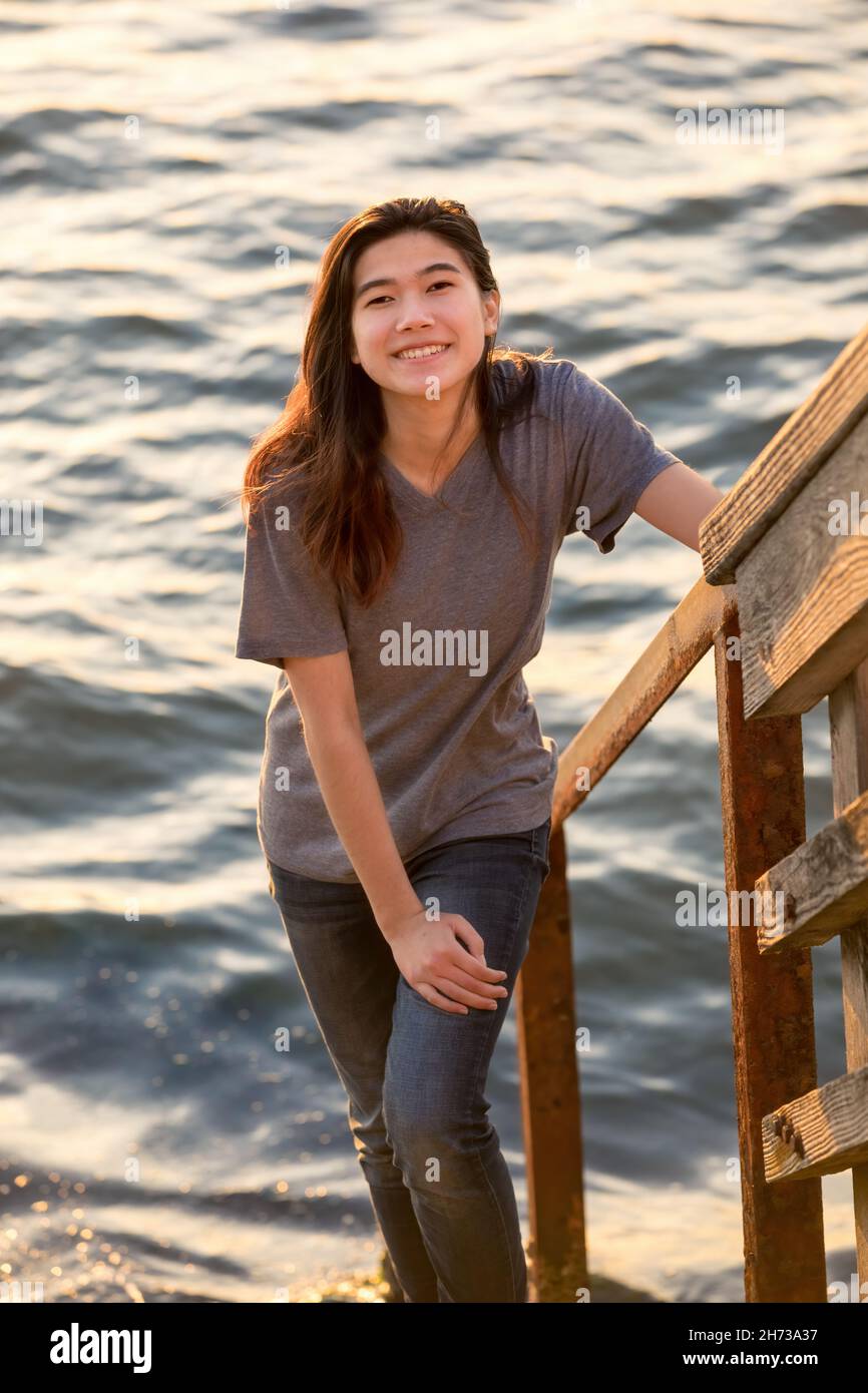 Biracial Asian teen girl standing on stone steps leading down to water Stock Photo