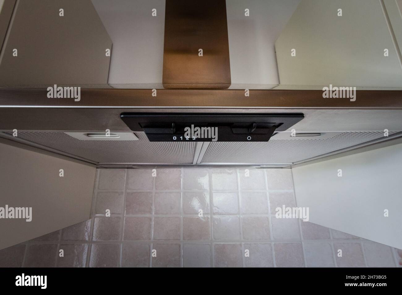 Picture of a consumer grad kitchen hood. A kitchen hood, exhaust hood, or range hood is a device containing a mechanical fan that hangs above the stov Stock Photo