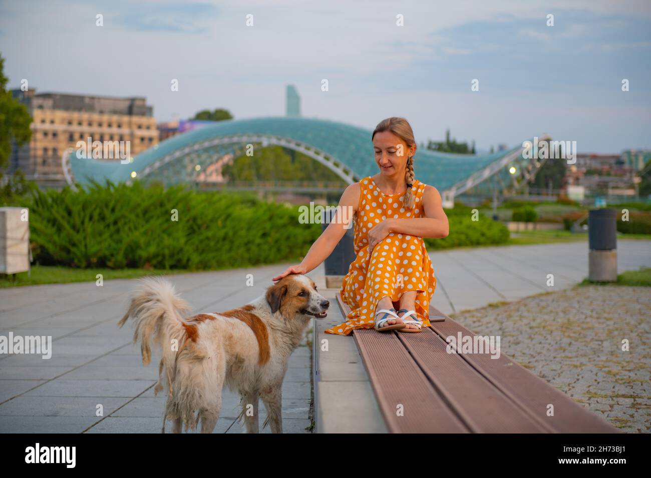 girl sitting on a bench with a dog in tbilisi Stock Photo - Alamy
