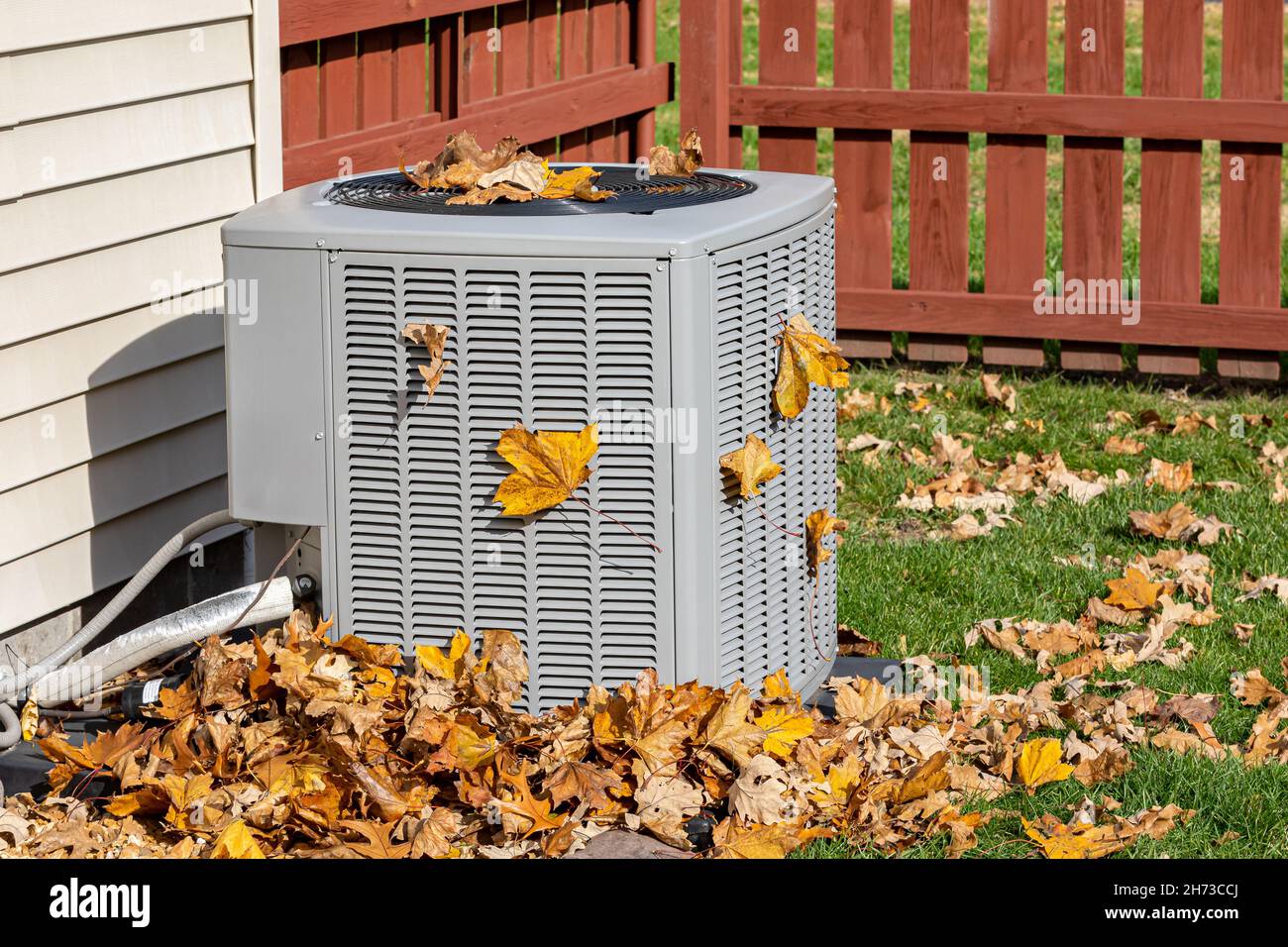 Dirty air conditioning unit covered in leaves during autumn. Home air conditioning, HVAC, repair, service, fall cleaning and maintenance concept. Stock Photo