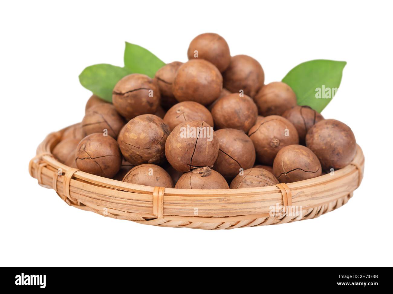 Macadamia nuts with leaves in a straw basket isolated on white background Stock Photo