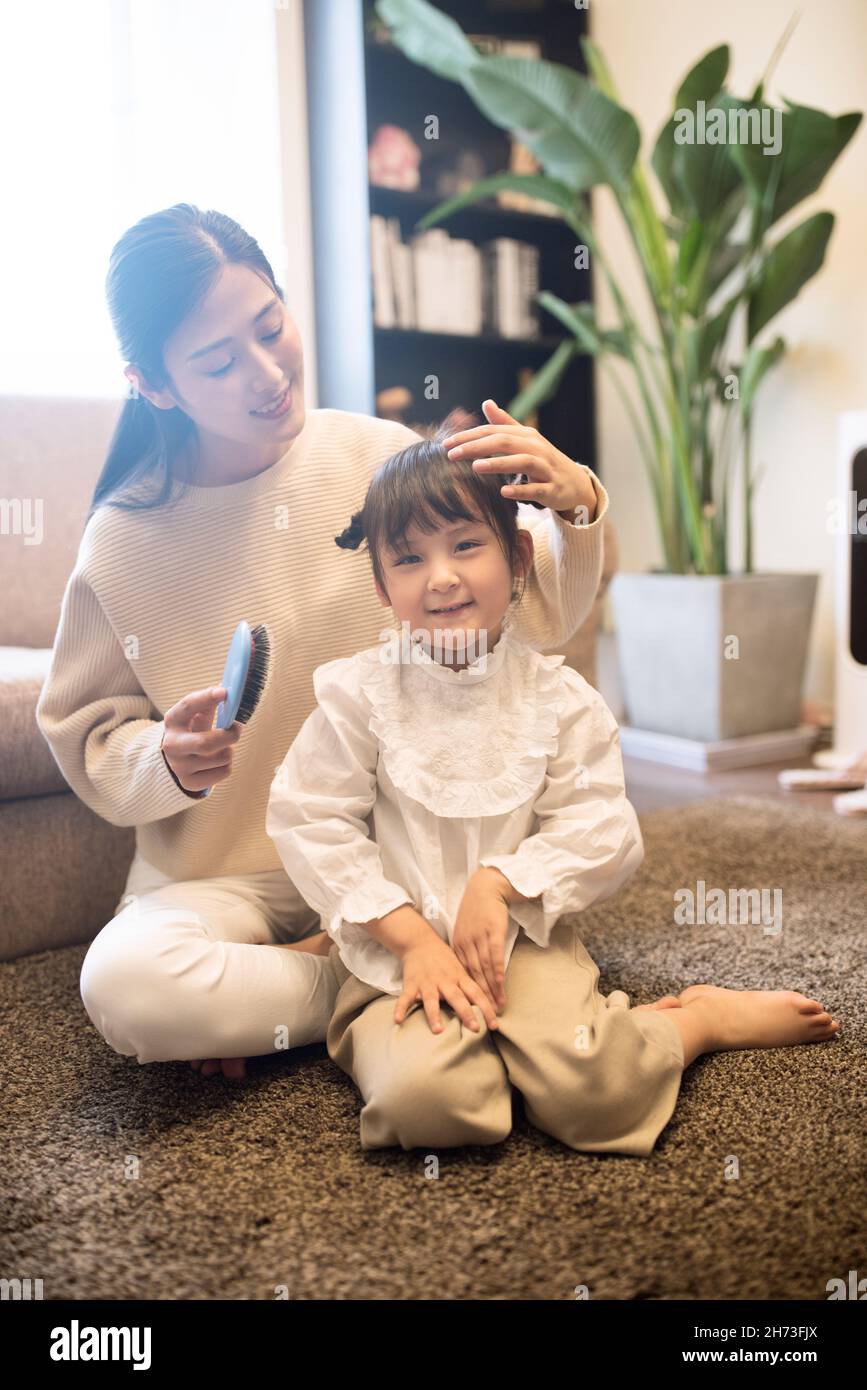 Mother combing her daughter's hair Stock Photo